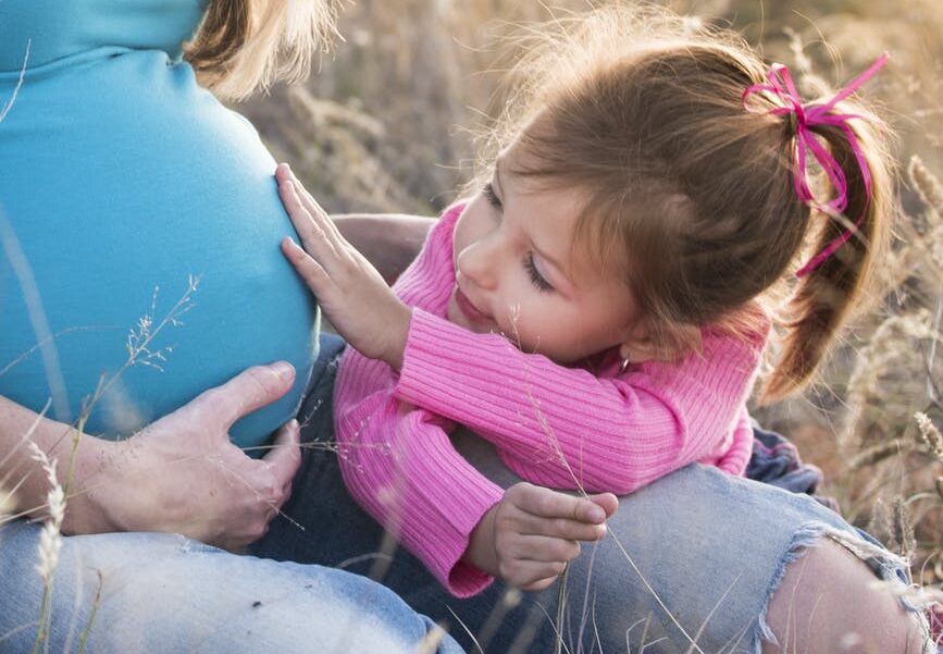 child touching the belly of a pregnant woman